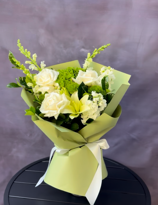 Bouquet of white and green flowers wrapped in green paper on a dark surface with a purple background